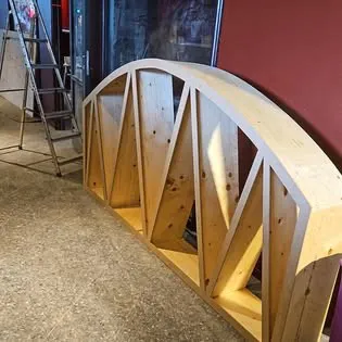 Välvt parti i ljust massivt trä med diagonala stag, sett snett från sidan